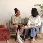 A therapist and a client sit together in a comfortable, sunlit room having a meaningful conversation, representing the compassionate, accessible mental health support offered through Harvest House’s Wellness Within Reach program.
